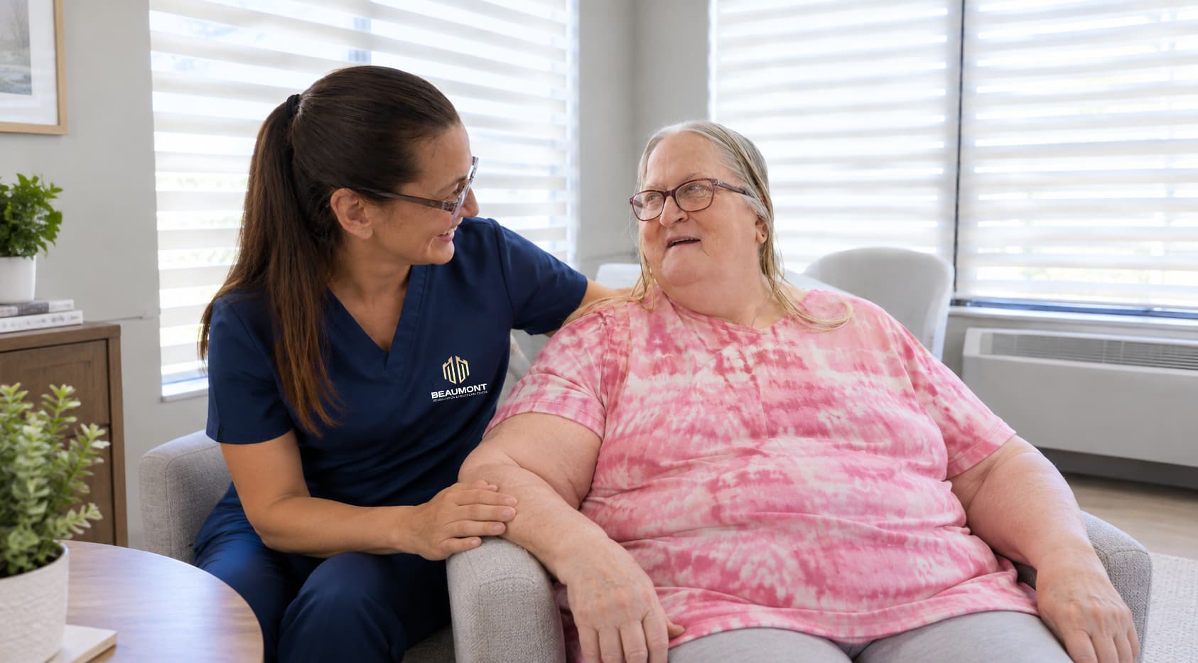 A caregiver sitting with a resident, the two of them laughing together
